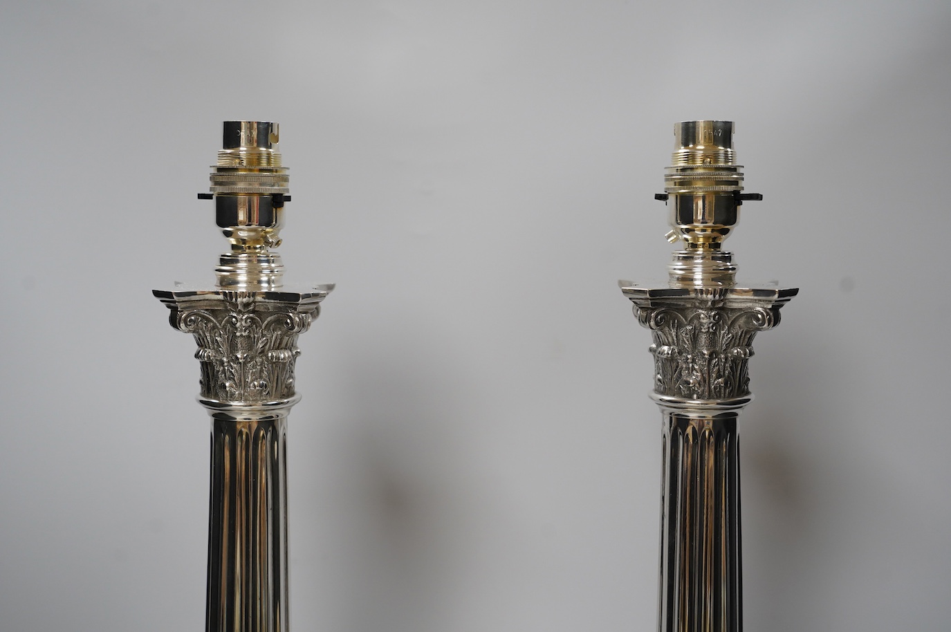 A pair of plated Corinthian column lamp bases, 56cm high including fitting. Condition - good